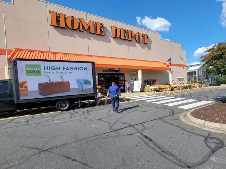 digital mobile billboards for advertising with a message from Home Sense "always-new arrivals always-on savings" displaying green and purple sofa in front of Home Depot