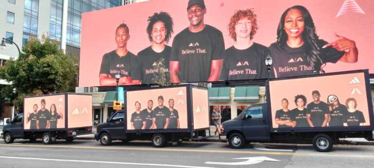 3 Mobile Digital Billboard Trucks displaying an Adidas campaign with diverse models parked in front of a digital billboard with same ad.