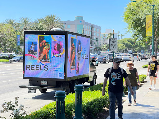 Cantmiss.US Digital mobile billboard parked on a busy street with people walking. The LED truck is showing an ad for Instagram Reels.