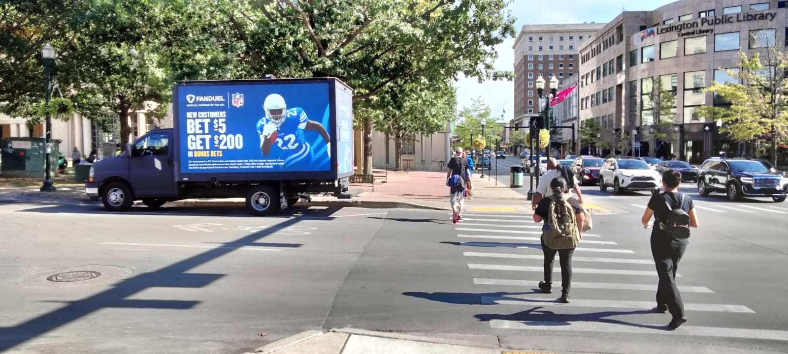 Cantmiss.us digital mobile billboard truck parked on the side of street with an image of a NFL player next to a Fandeul Ad for new customers.