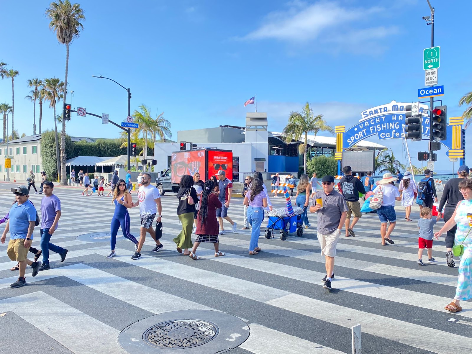The Image highlights Mobile Billboards Are Better Option to Traditional Billboards in Pedestrians crossing street at Santa Monica, California.