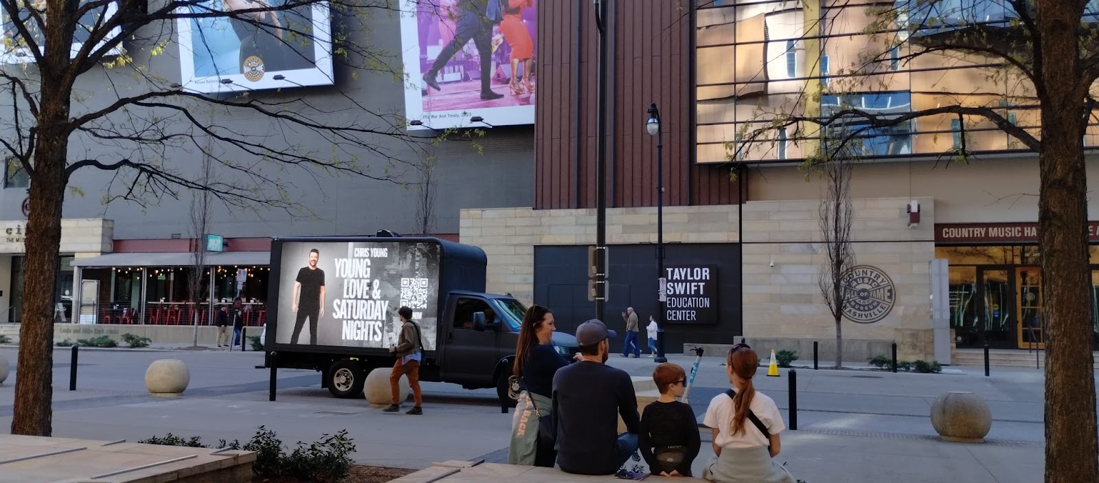 Billboards on trucks ad for Chris Young parked beside a side walk with a crowd in front of Country Music Hall of Fame in Nashville.
