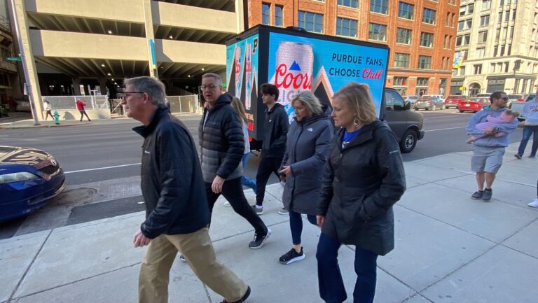 six people passing to a mobile billboard truck advertising a message from Chill with a message saying "PURDUE FANS, Choose Chill