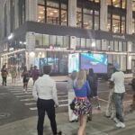 Ad truck for Gorgon City promoting Arc music festival. Pedestrians walking in front of WeWork building and Lululemon store in Detroit at night.