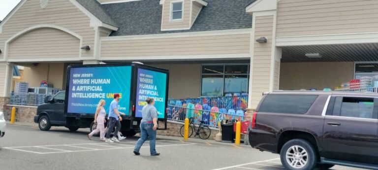 People walking past an ad trucks for This Is New Jersey with an AI advertisement outside a store in Atlantic City. Shoppers passing by.